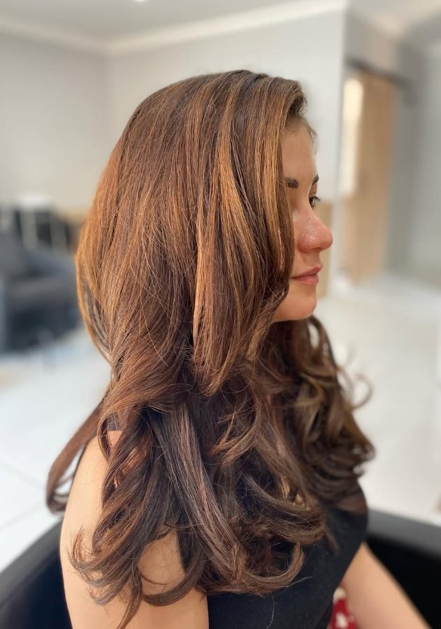 Glossy brunette hair with caramel highlights and bouncy curls