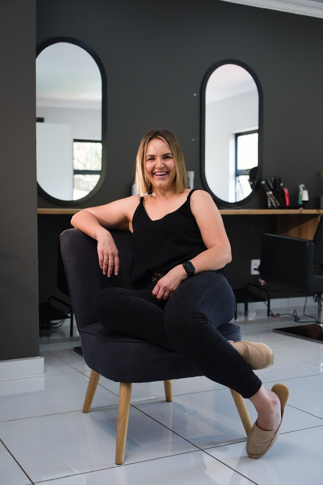 Leandri Darlington seated in her salon in front of two oval mirrors